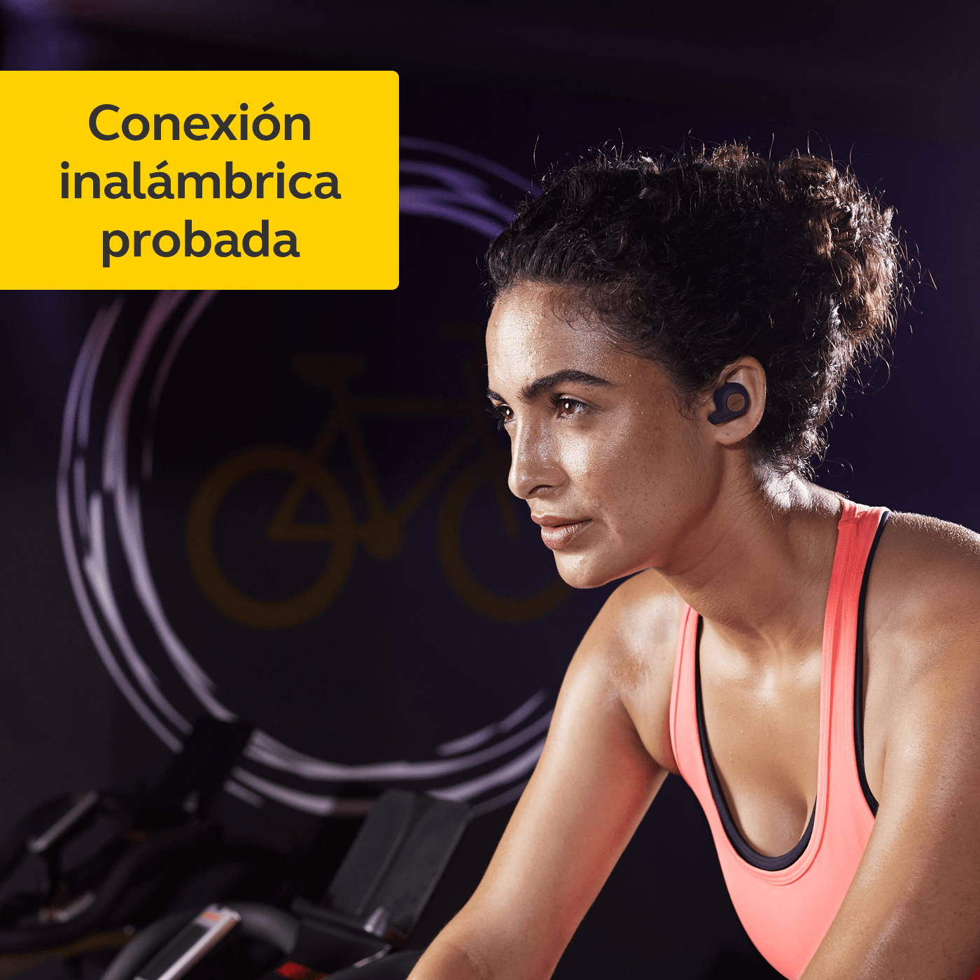Mujer usando auriculares inalámbricos en interiores. Una imagen de bicicleta en la pared.