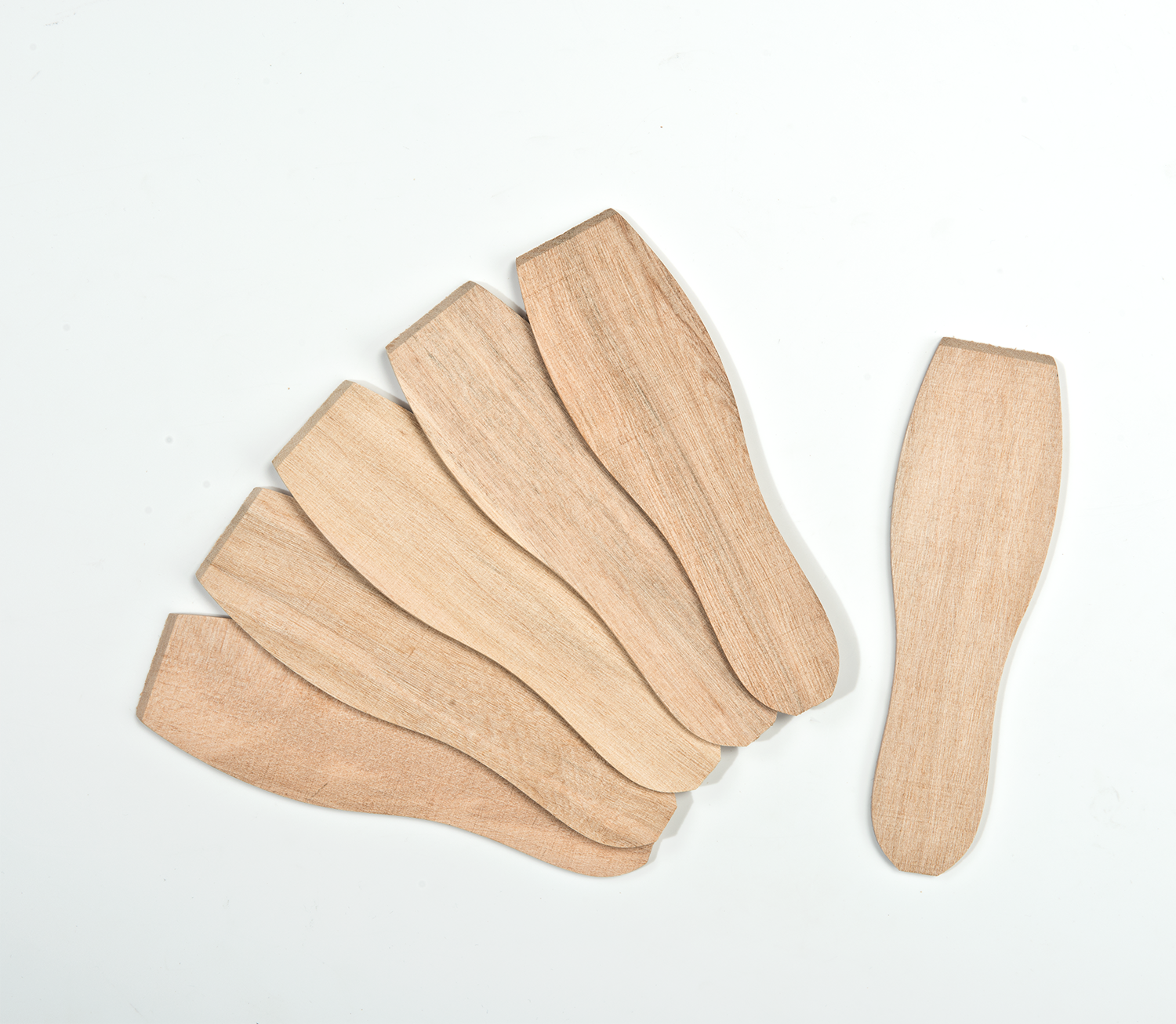 Wooden ice cream spoons spread out on a white surface.