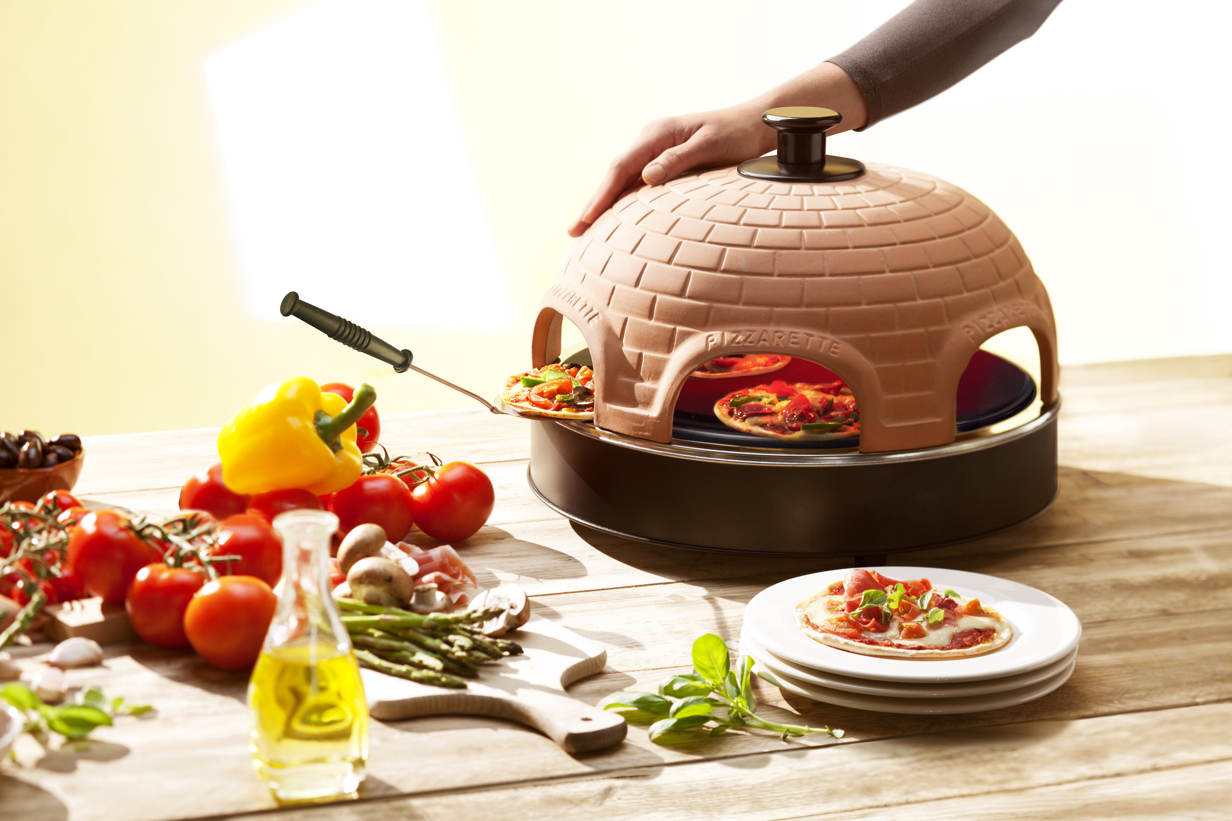 Pizzaofen mit zwei Pizzas im Inneren. Gemüse ist links und eine Pizza rechts.