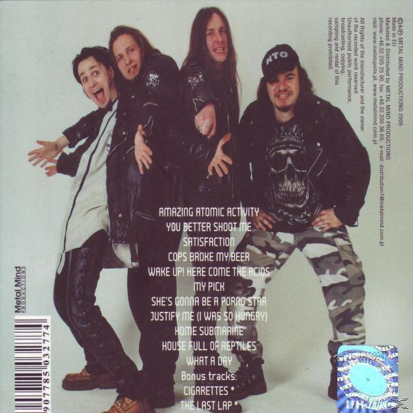Bandfoto. Vier Männer posieren, lächeln und schauen in die Kamera. Album-Trackliste befindet sich hinter ihnen.