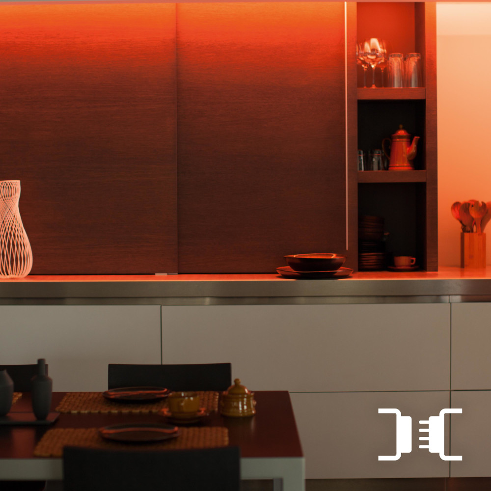Une scène de cuisine moderne avec une table, des armoires et une lumière orange chaude.