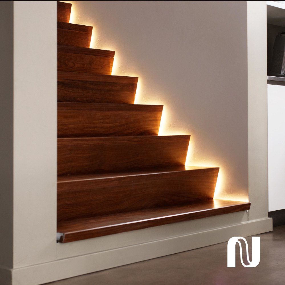 Escalier en bois avec lumières sous chaque marche et murs blancs.