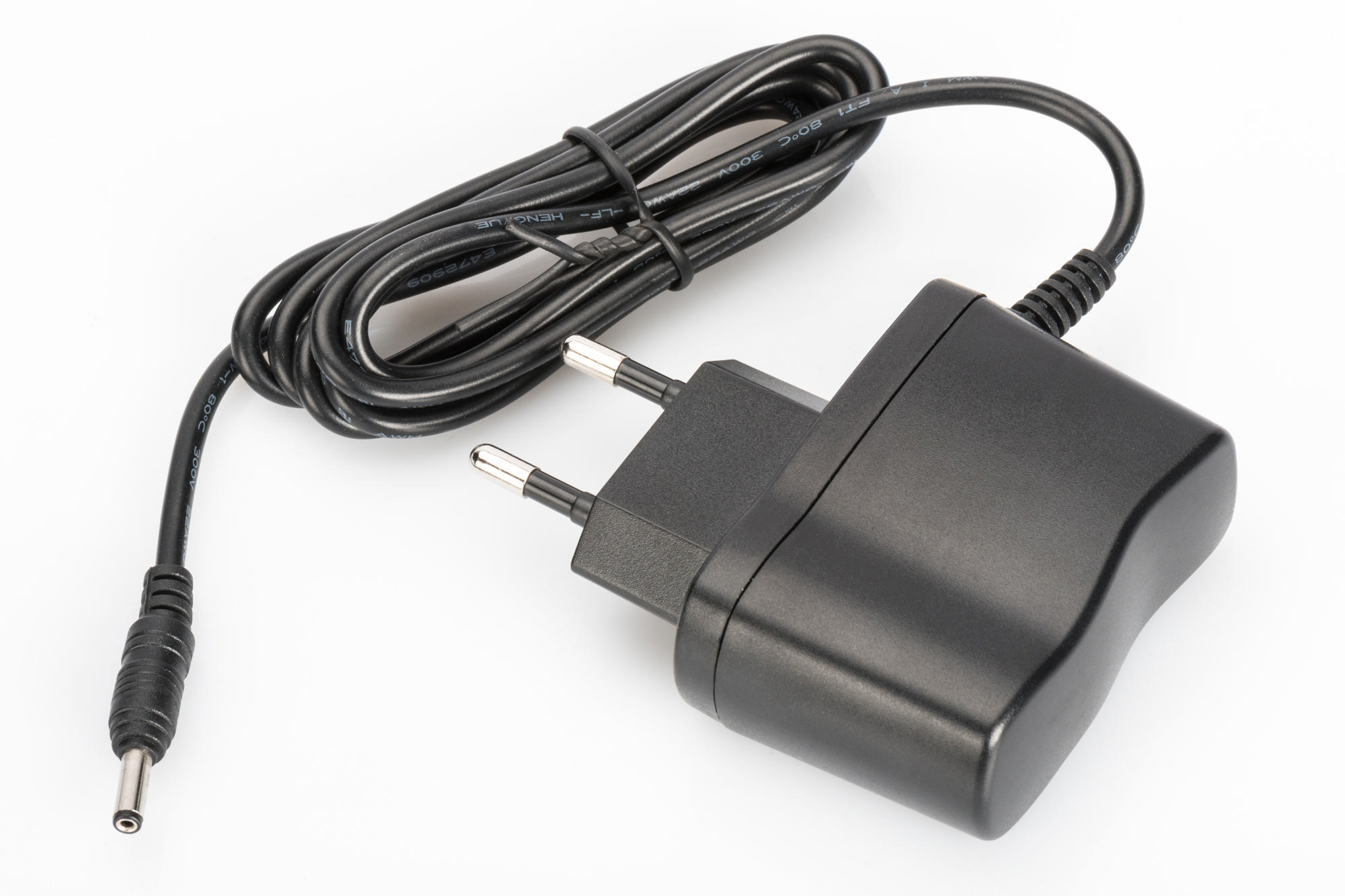 Schwarzes Netzteil mit Stecker und Kabel, auf weißem Hintergrund.