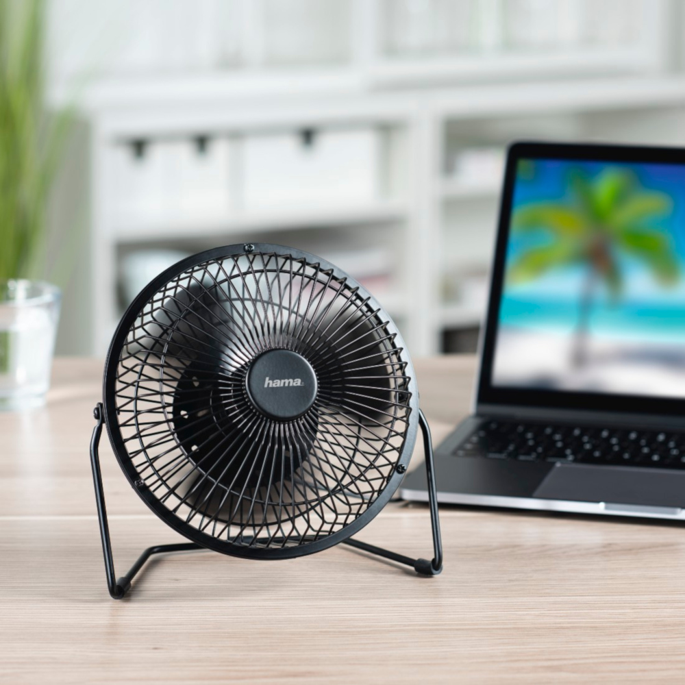 Petit ventilateur de bureau noir sur un bureau en bois.
