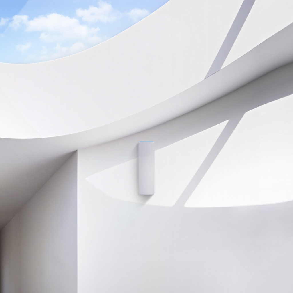 Muro bianco con un oggetto rettangolare bianco e cielo blu.