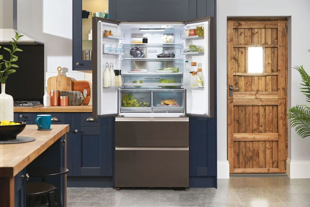 Un refrigerador abierto con comida dentro en una cocina azul marino.