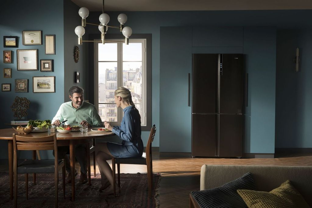 Pareja cenando en una habitación con una gran ventana y una nevera negra.