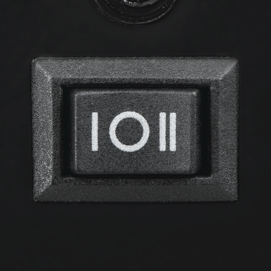 Bouton d'alimentation noir. Symboles blancs I et O. Placé dans un carré noir encastré.