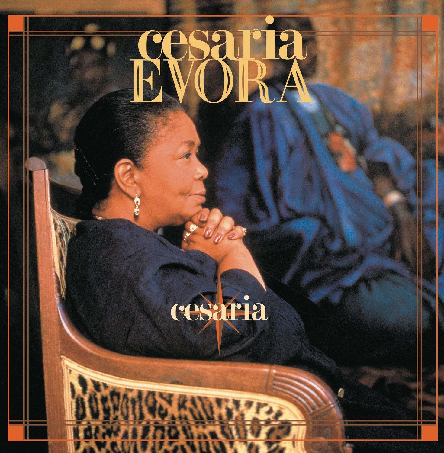 Cesaria Evora egy széken ül, album borító. A háttérben egy kék ruhás személy látható.