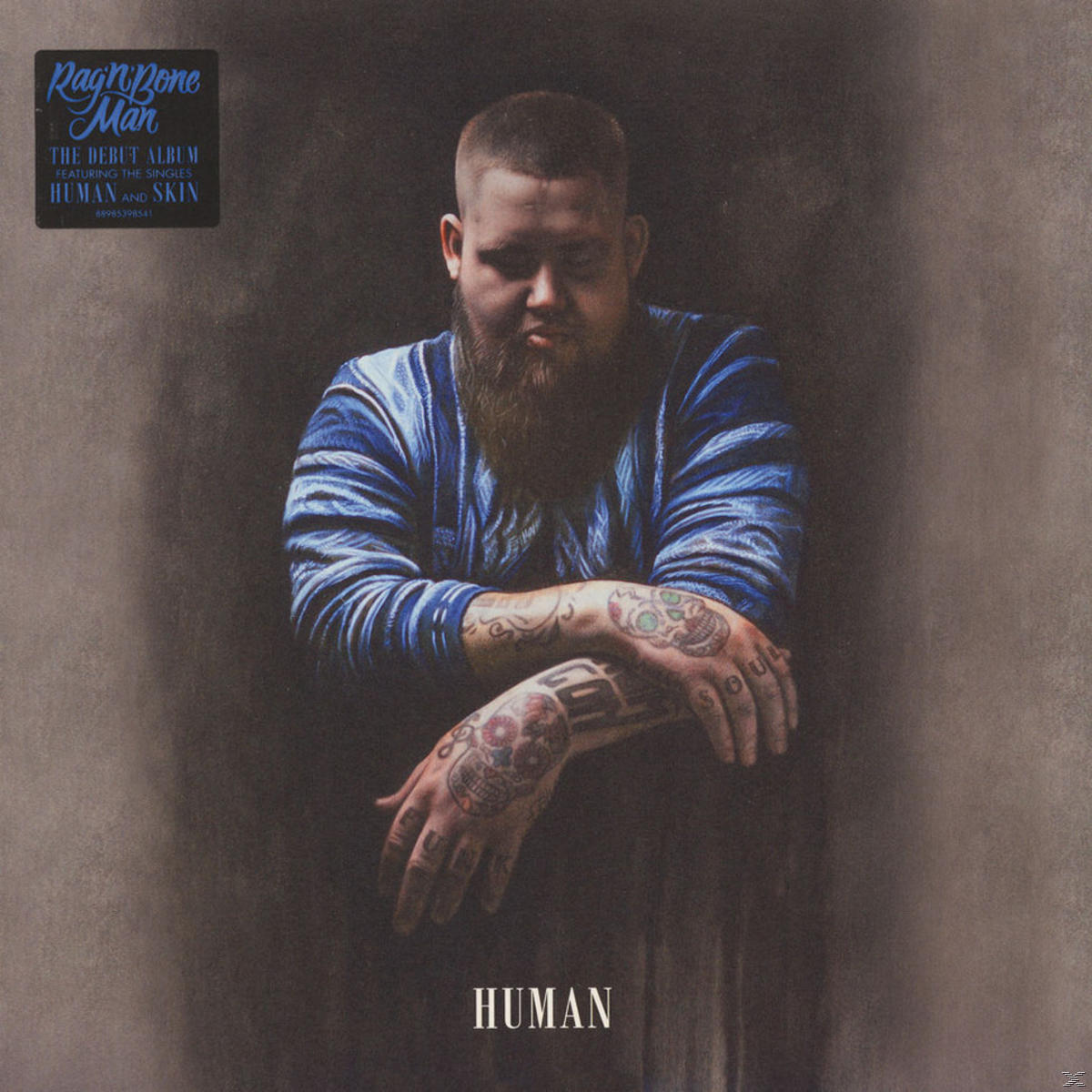 RagnBone Man Albumcover. Mann mit Bart und Tattoos. Albumtitel 'Human' auf grauem Hintergrund.