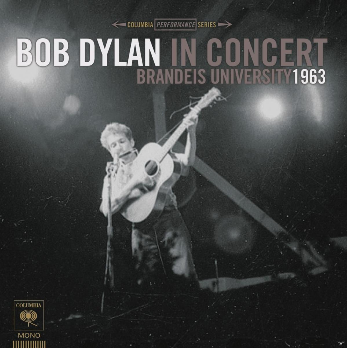 Bob Dylan im Konzert, Gitarre spielend, mit Text und verschwommenem Hintergrund.