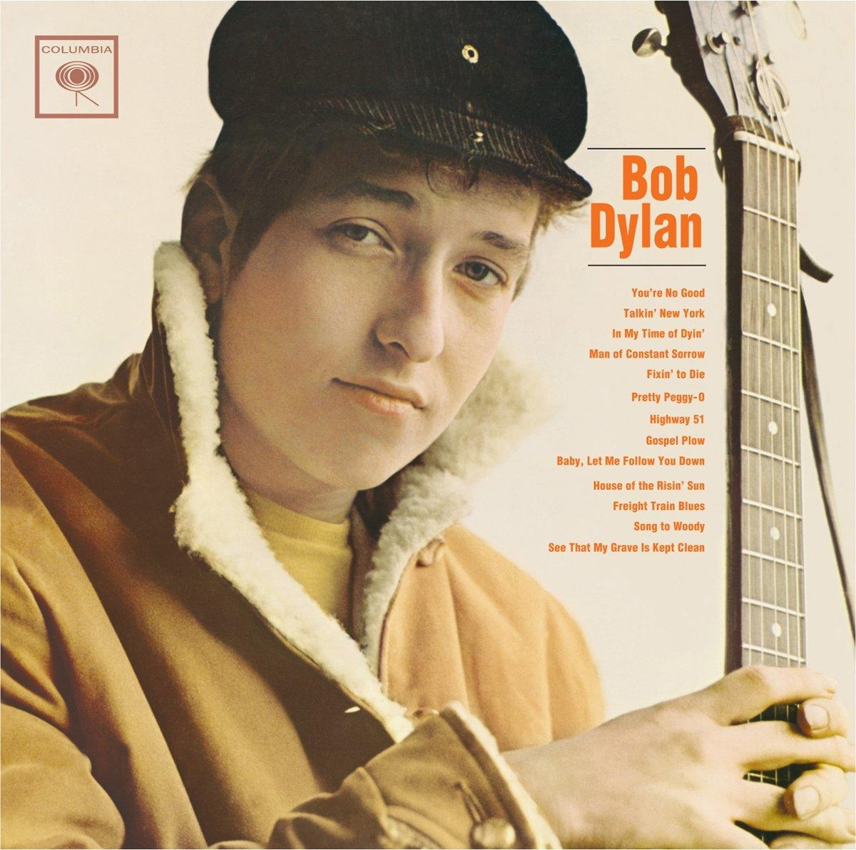 Bob Dylan Albumcover. Er trägt einen Hut und eine Jacke und hält eine Gitarre. Der Hintergrund ist hell.