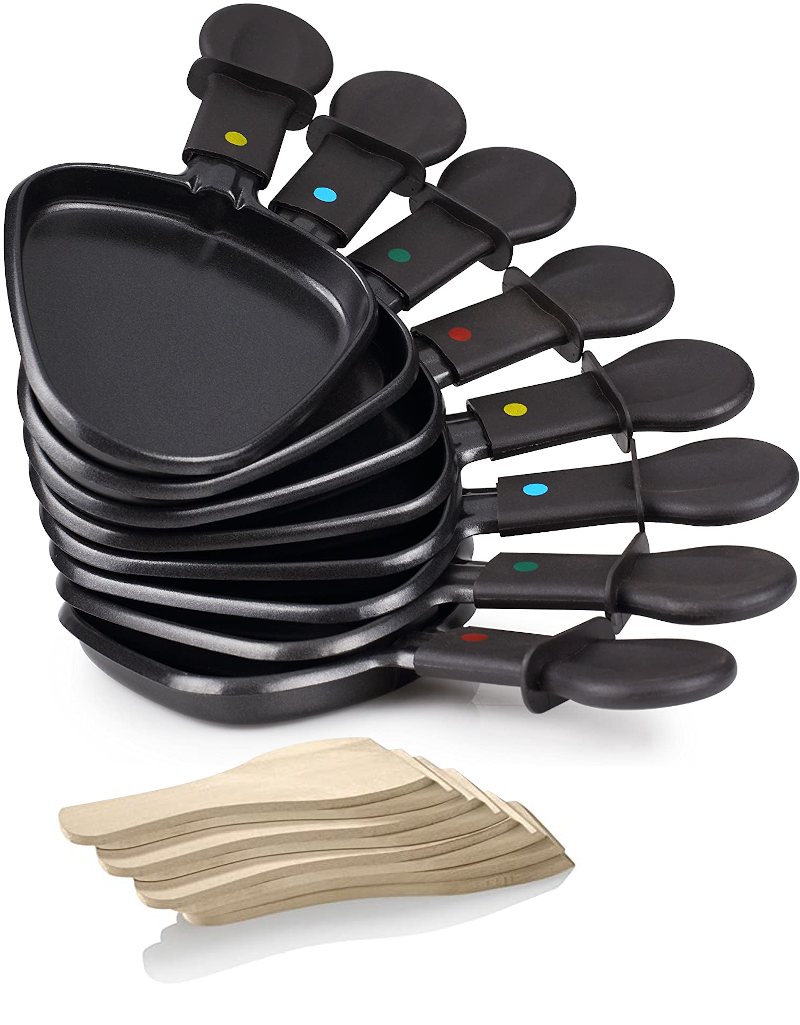 Raclette serpenyők és fa spatulák, egymásra rakva. Fekete serpenyők, fehér háttér.