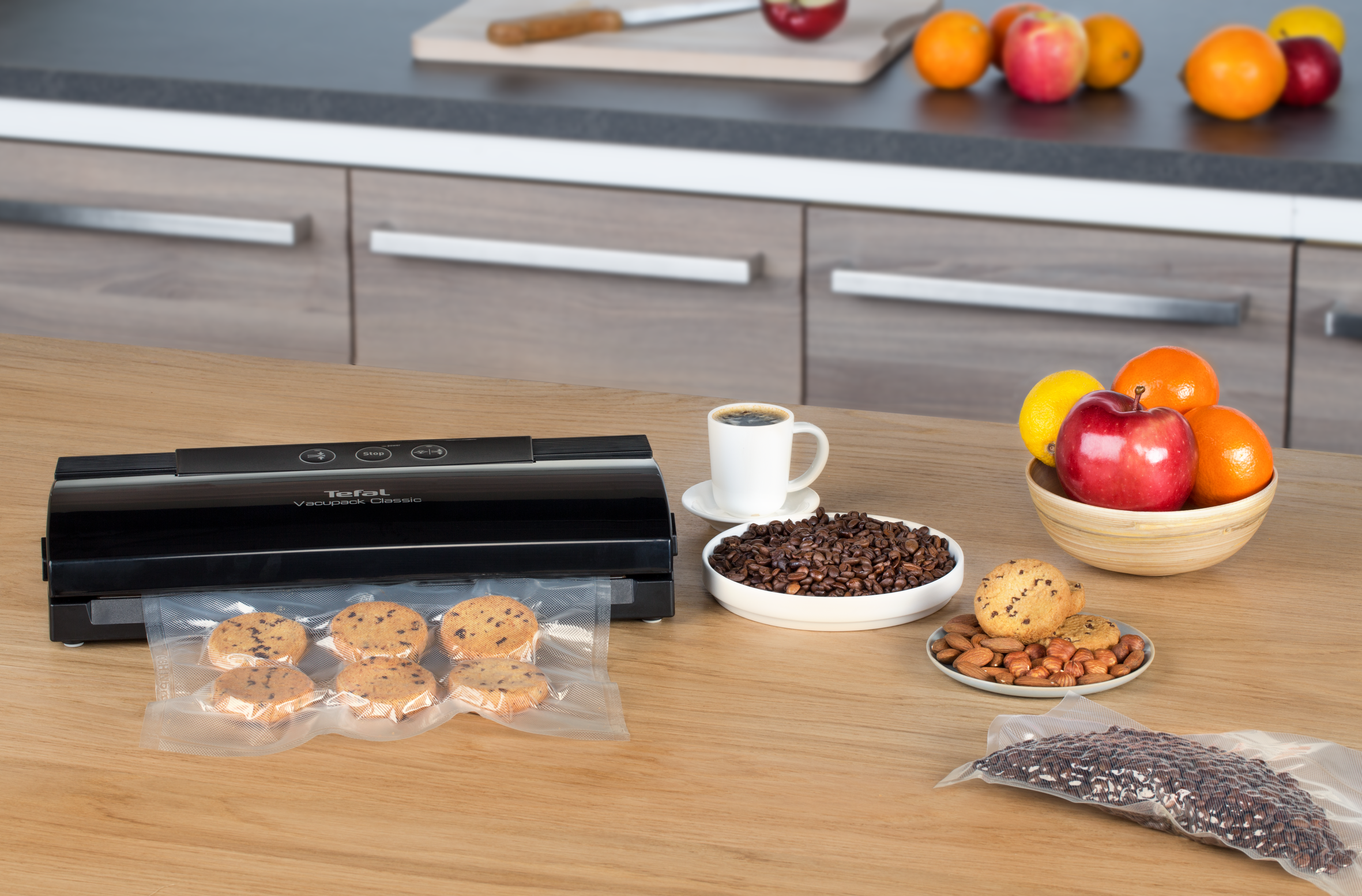A vacuum sealer with cookies, nuts, and coffee beans in bags on a table.