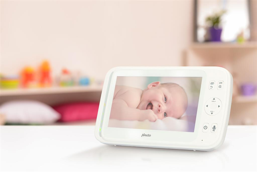 Ein weißer Babyphone zeigt ein lächelndes Baby in einem Raum.