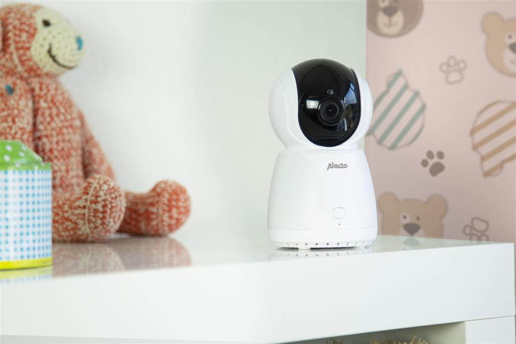 Babyphone-Kamera, weiß, auf einem Regal mit einem Stofftier und einer gemusterten Wand.