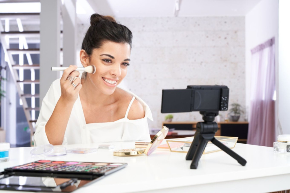 Een vrouw neemt een make-uptutorial op en brengt blush aan.