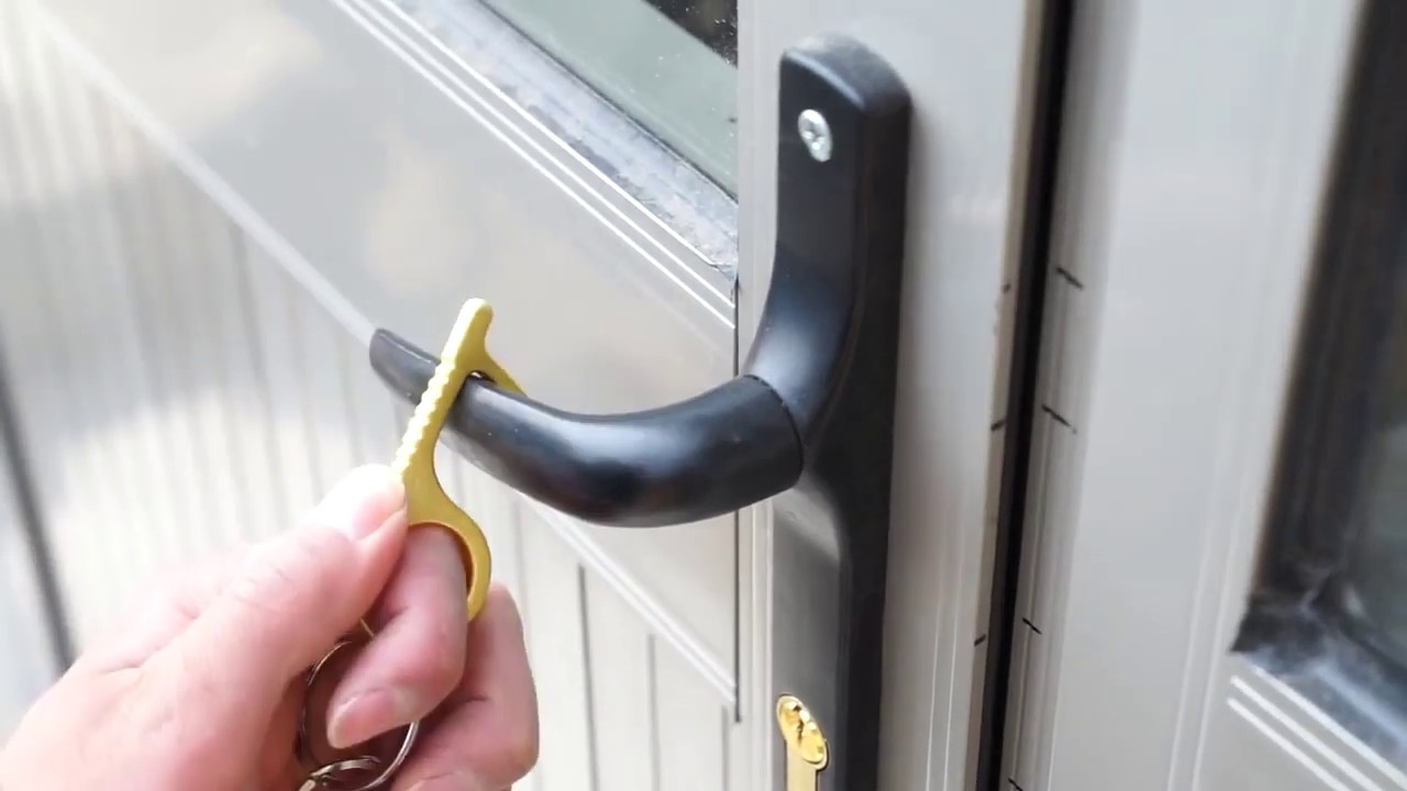 Una mano usando una herramienta amarilla para abrir una manija de puerta.