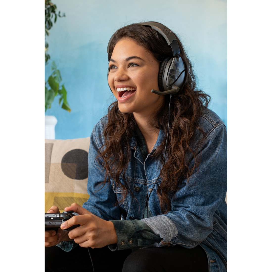 Frau spielt Spiel, trägt Headset, lächelt. Hält Controller.