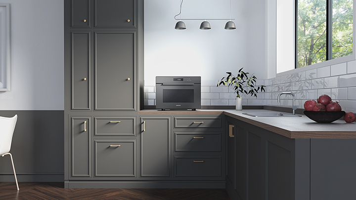 Moderne grijze keuken met kasten, een magnetron en een raam.