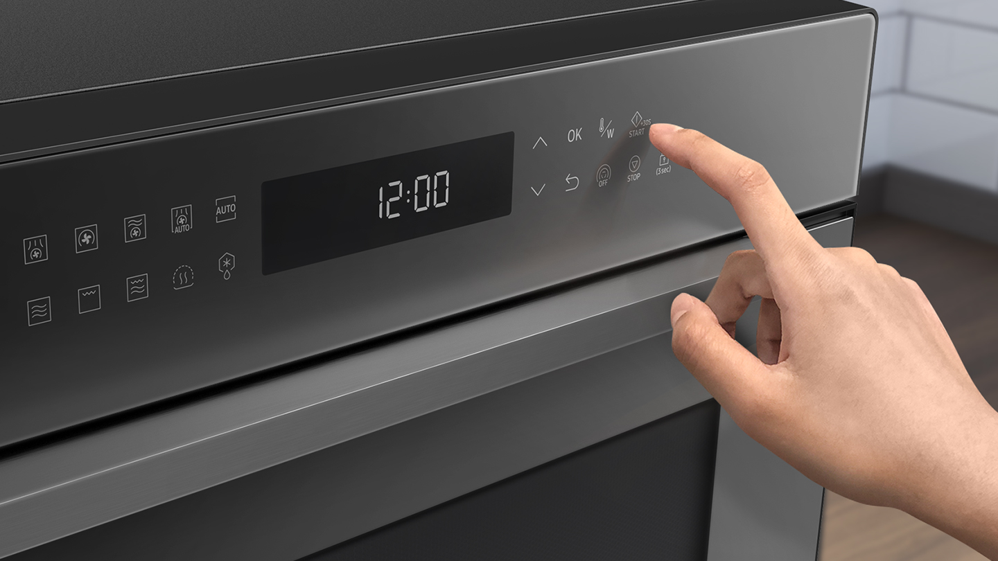 Hand drukt op de startknop op een donker ovenbedieningspaneel.