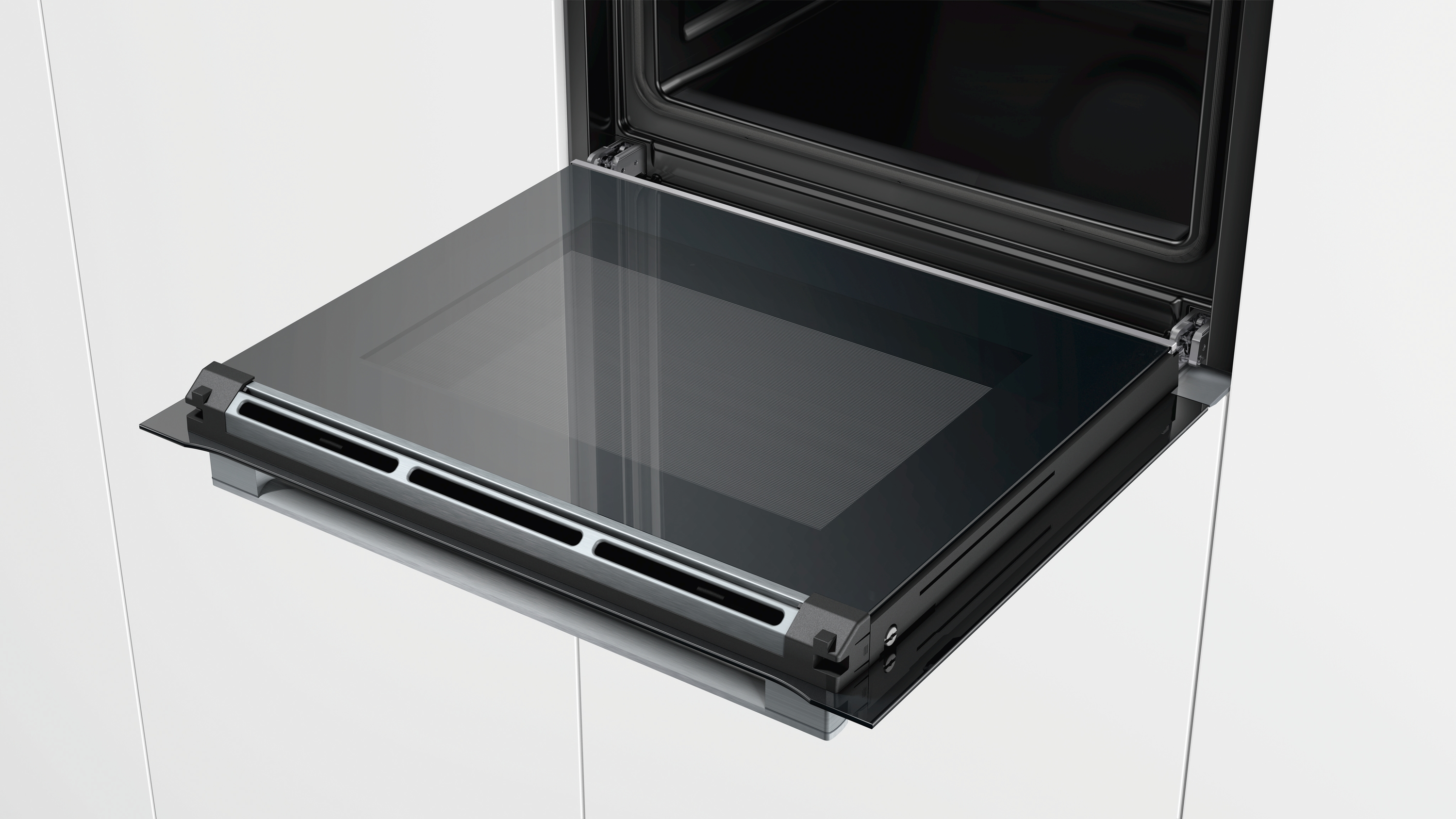 Four ouvert avec la porte vitrée étendue. Le four est dans une cuisine blanche.