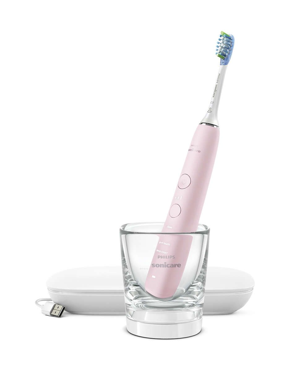 Rosa elektrische Zahnbürste in einem Glas. Die Ladestation und ein USB-Kabel sind ebenfalls vorhanden.