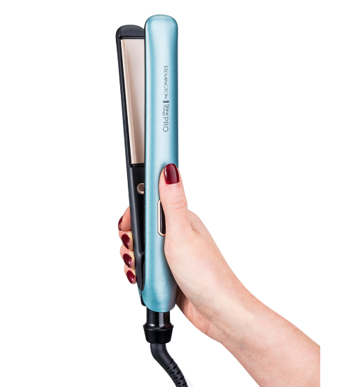 Mano de mujer sosteniendo una plancha para el cabello azul, aislada sobre blanco.