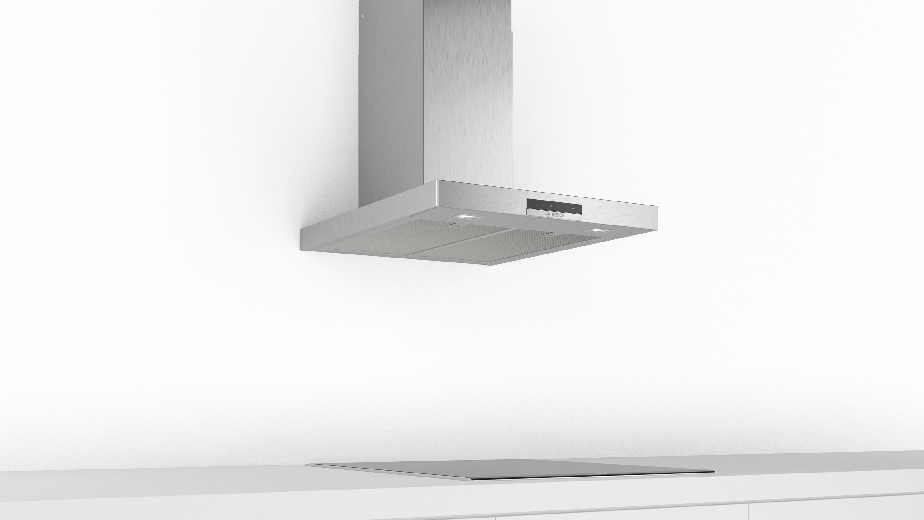 A silver range hood is mounted on a white wall above a black cooktop.