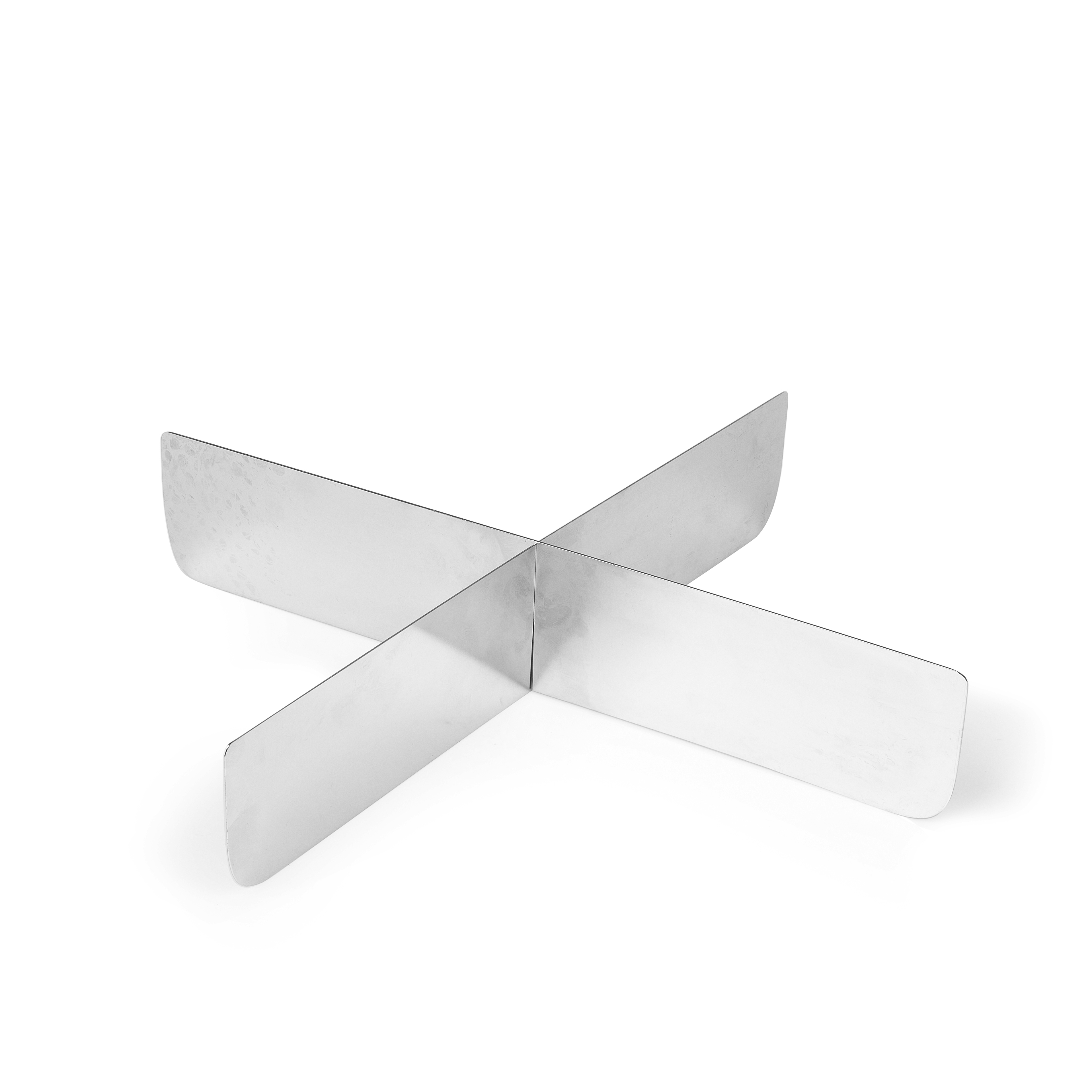A silver metal trivet in a cross shape, resting on a white surface.