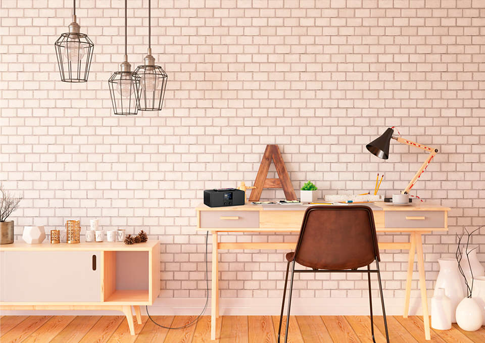 Gemütliches Homeoffice mit Schreibtisch und weißer Backsteinmauer. Moderne Lampen hängen darüber.