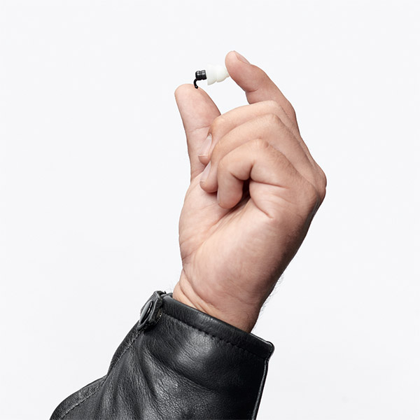 Een hand die een kleine, witte en zwarte oortelefoon vasthoudt.