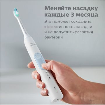 Main tenant une brosse à dents électrique blanche avec un bouton bleu.