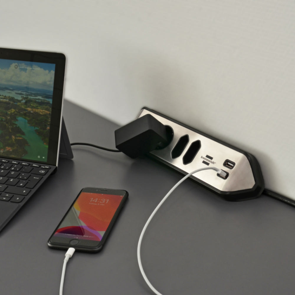 Eine Steckdosenleiste mit mehreren Steckdosen und USB-Anschlüssen, mit Telefon und Tablet.