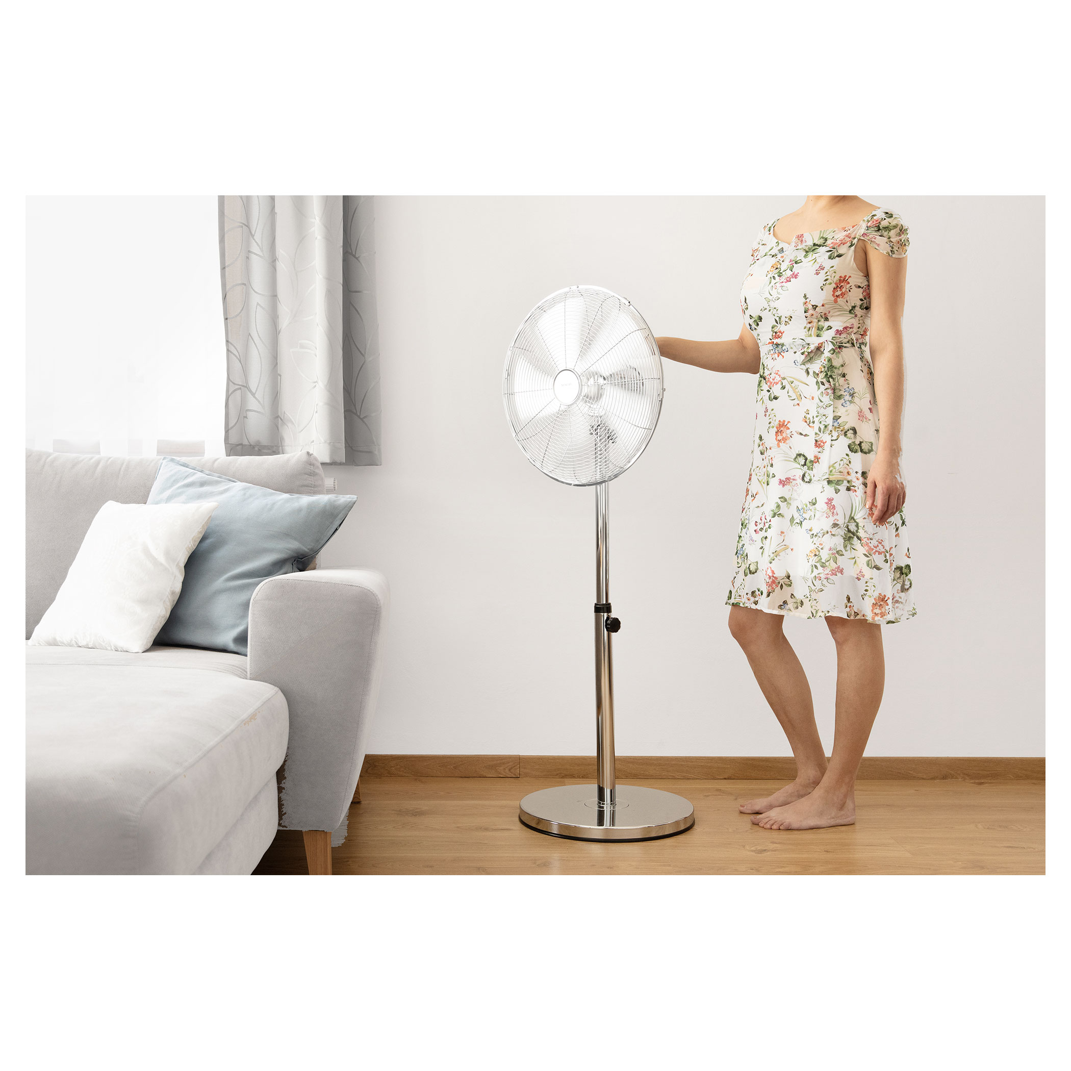 Nő egy ezüst ventilátornál.