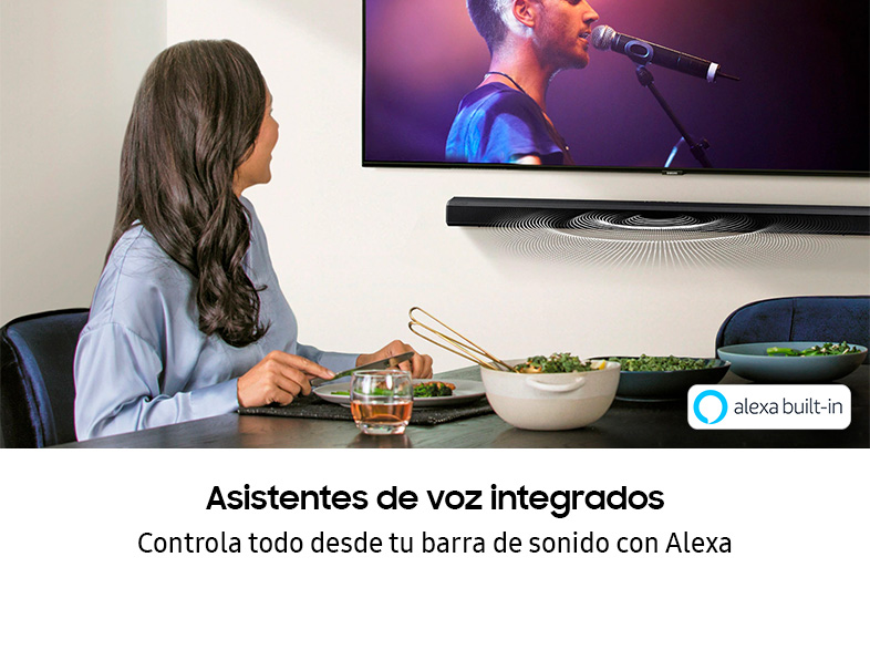 Una mujer comiendo frente a un televisor con barra de sonido. Se anuncia Alexa integrada.