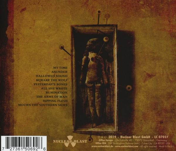 Albumcover mit einer puppenartigen Figur in einer Box, umgeben von Text und Logo.