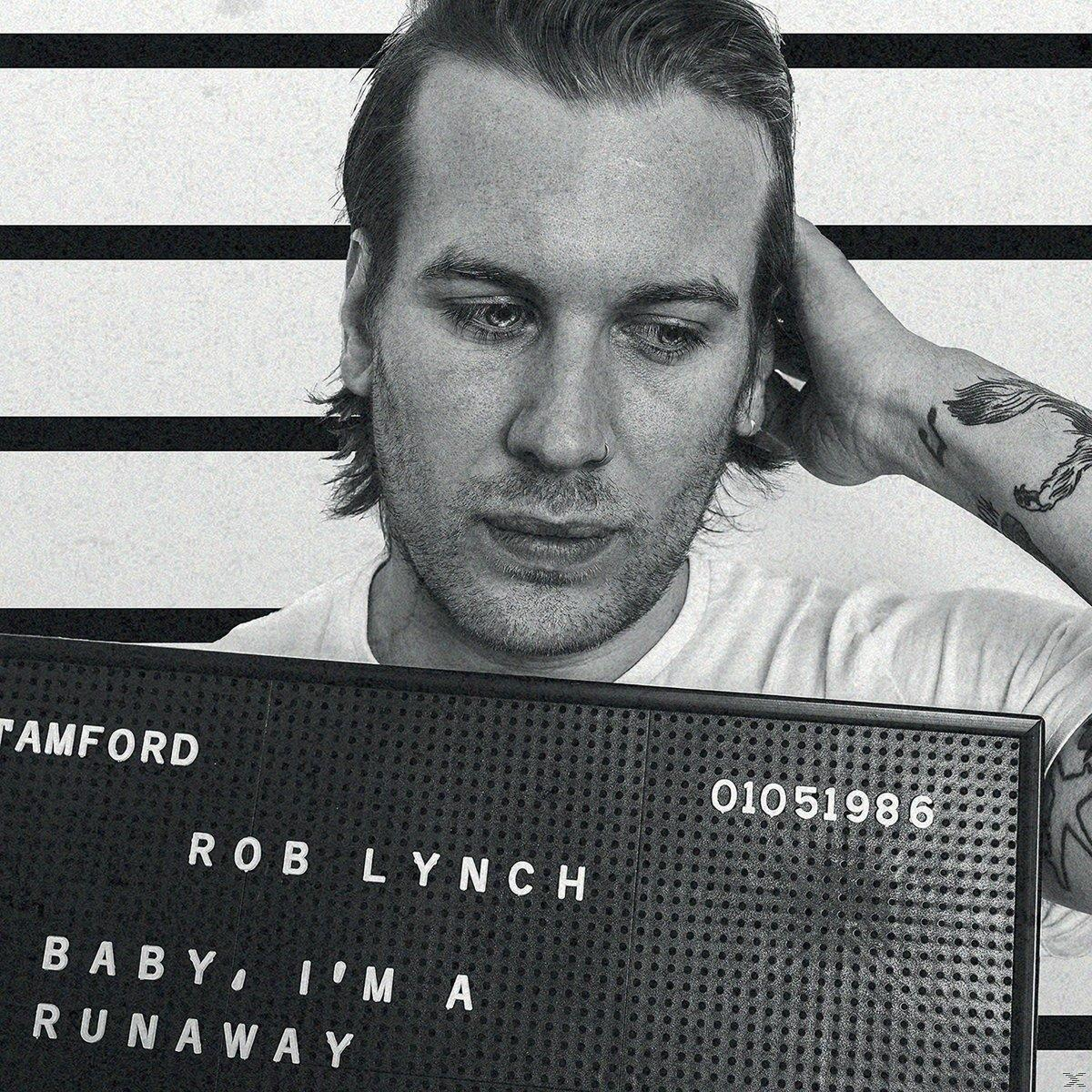 Egy tetovált férfi tart egy táblát: "TAMFORD ROB LYNCH BABY, I'M A RUNAWAY".
