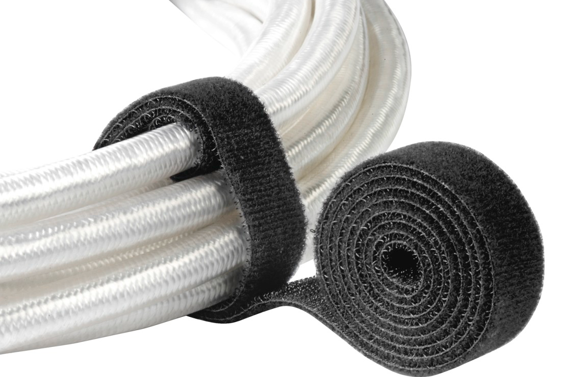 Ein Bündel weißer Kabel, gesichert mit einem schwarzen Klettverschluss und einer Klettverschlussrolle.