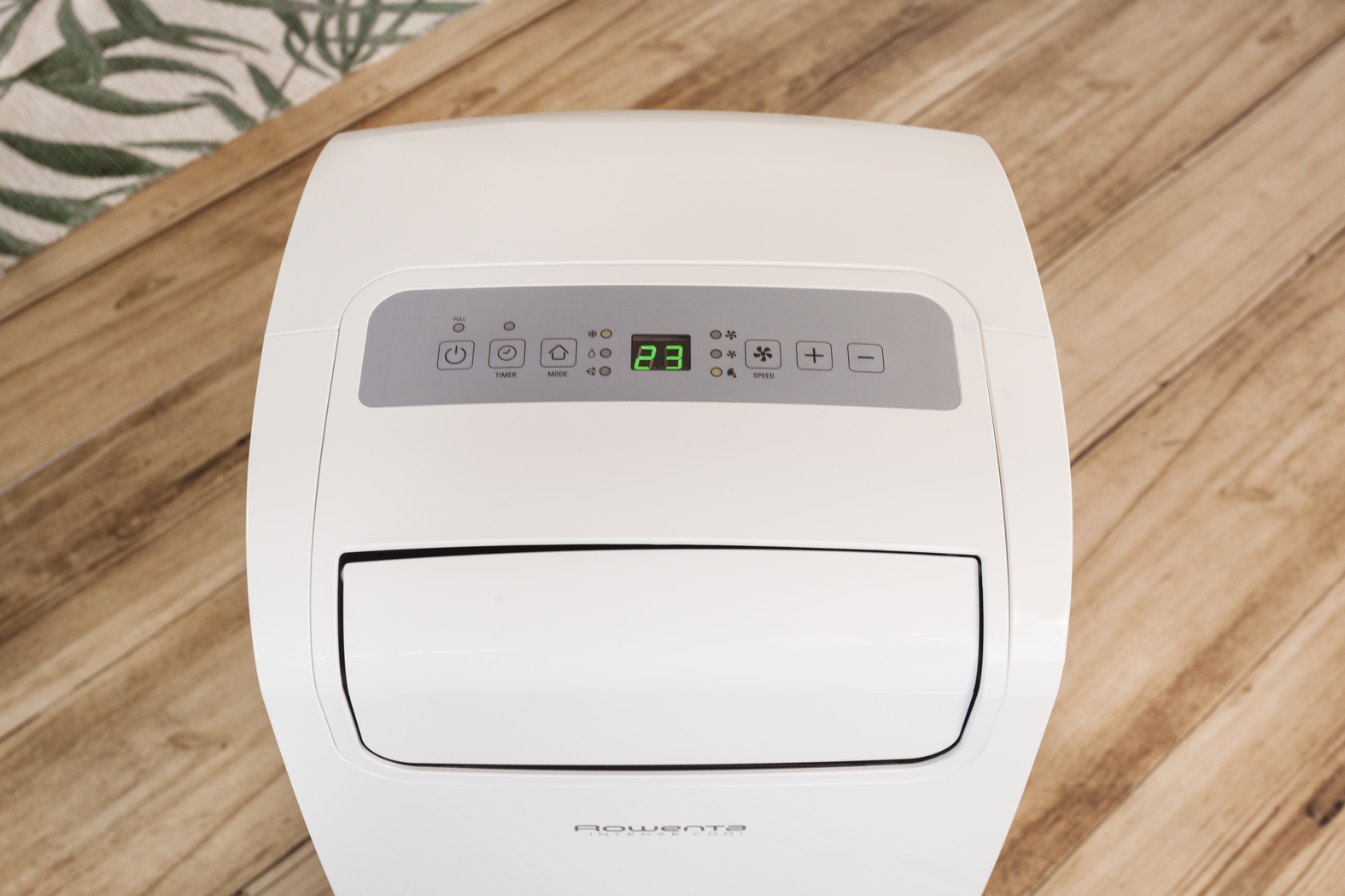 Aire acondicionado portátil blanco en un suelo de madera. Pantalla digital 88 grados.