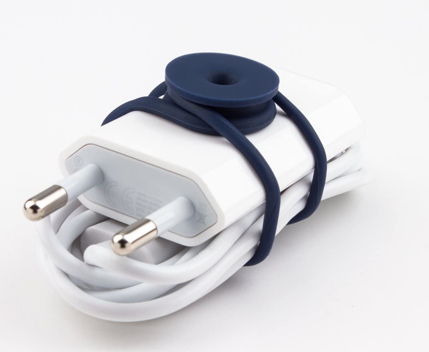 Un organisateur de câble bleu s'enroule autour d'un chargeur blanc. Fond blanc.