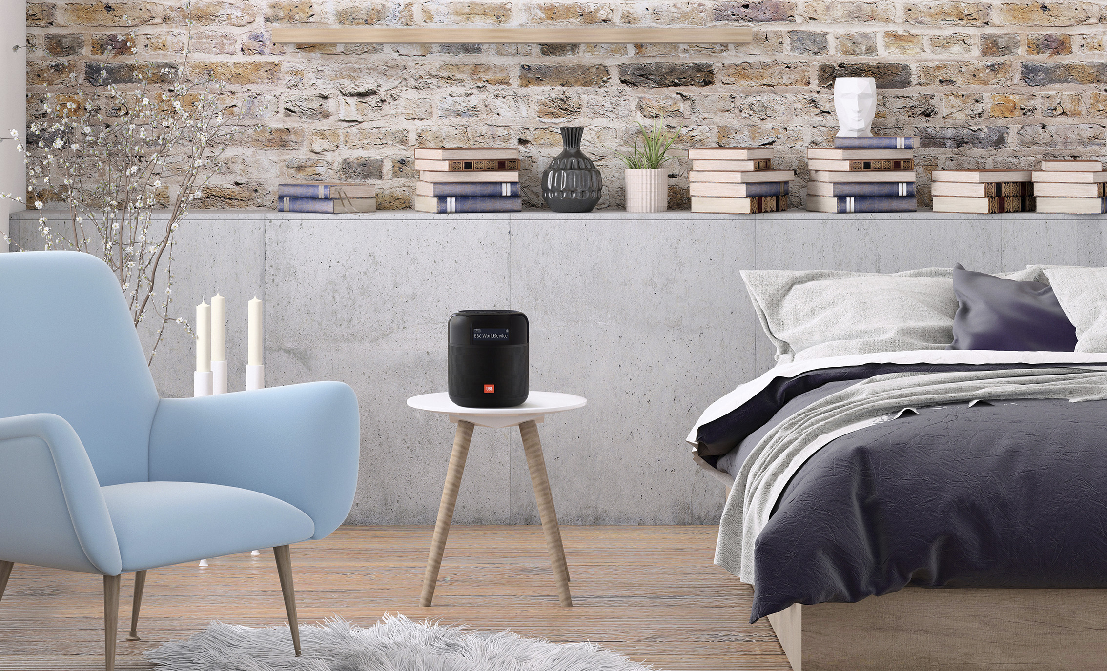 Room with a blue chair, books, and a speaker on a table, next to a bed.