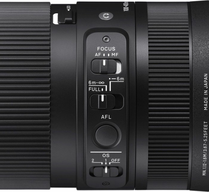 Schwarze Linse mit Fokus-, Zoom- und Modusreglern. Auf der Seite ist der Text „Made in Japan“ zu sehen.
