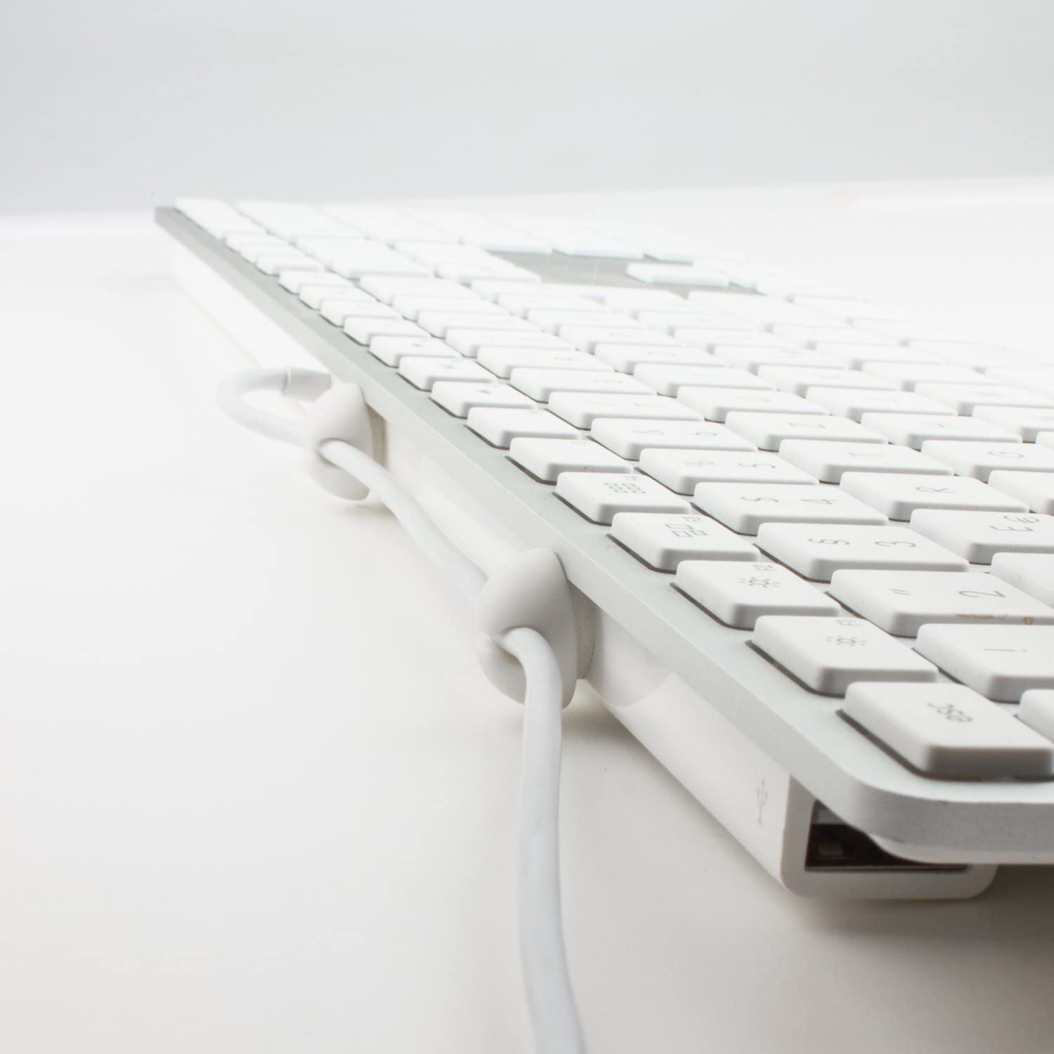 Primo piano di una tastiera bianca con cavo, che mostra tasti e gestione cavi.