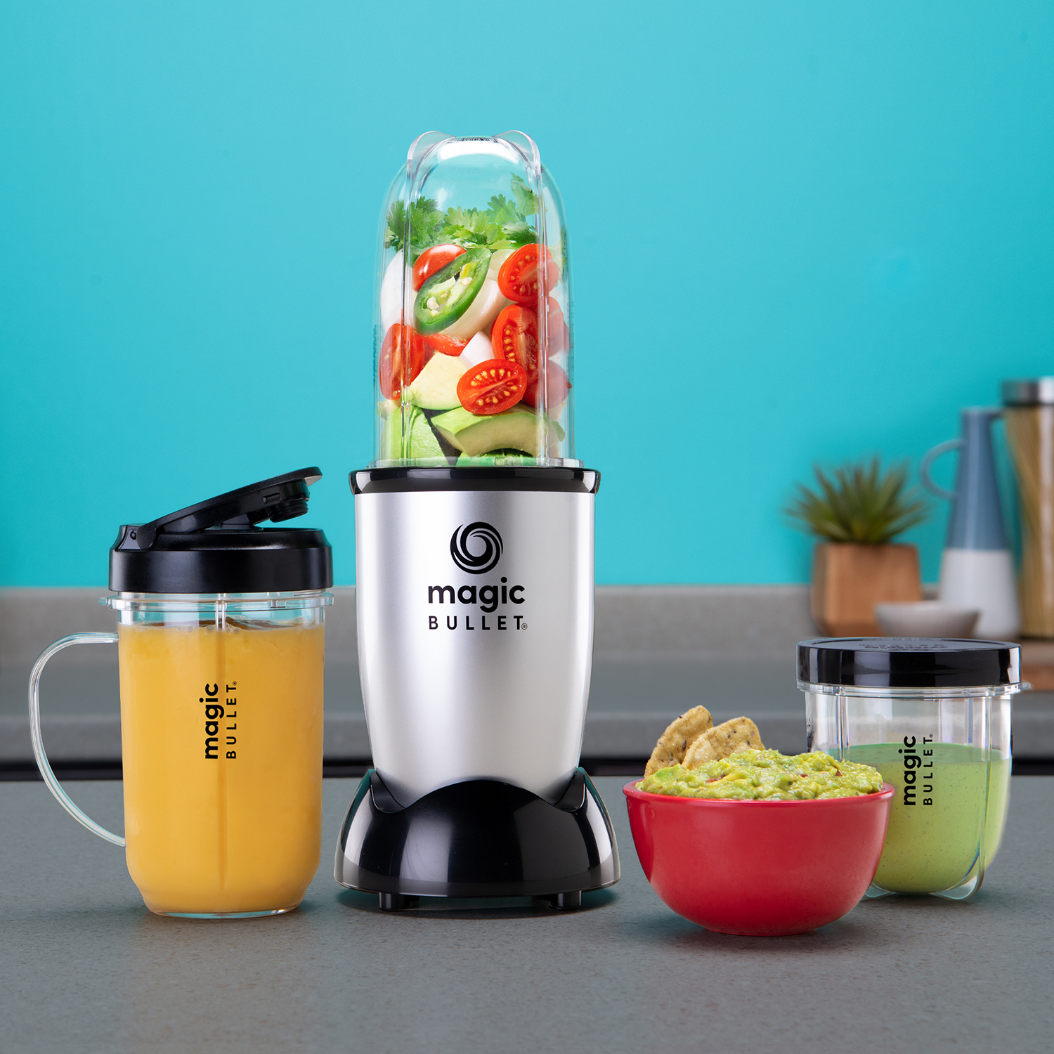 A Magic Bullet blender with ingredients and dips on a gray surface with a blue background.