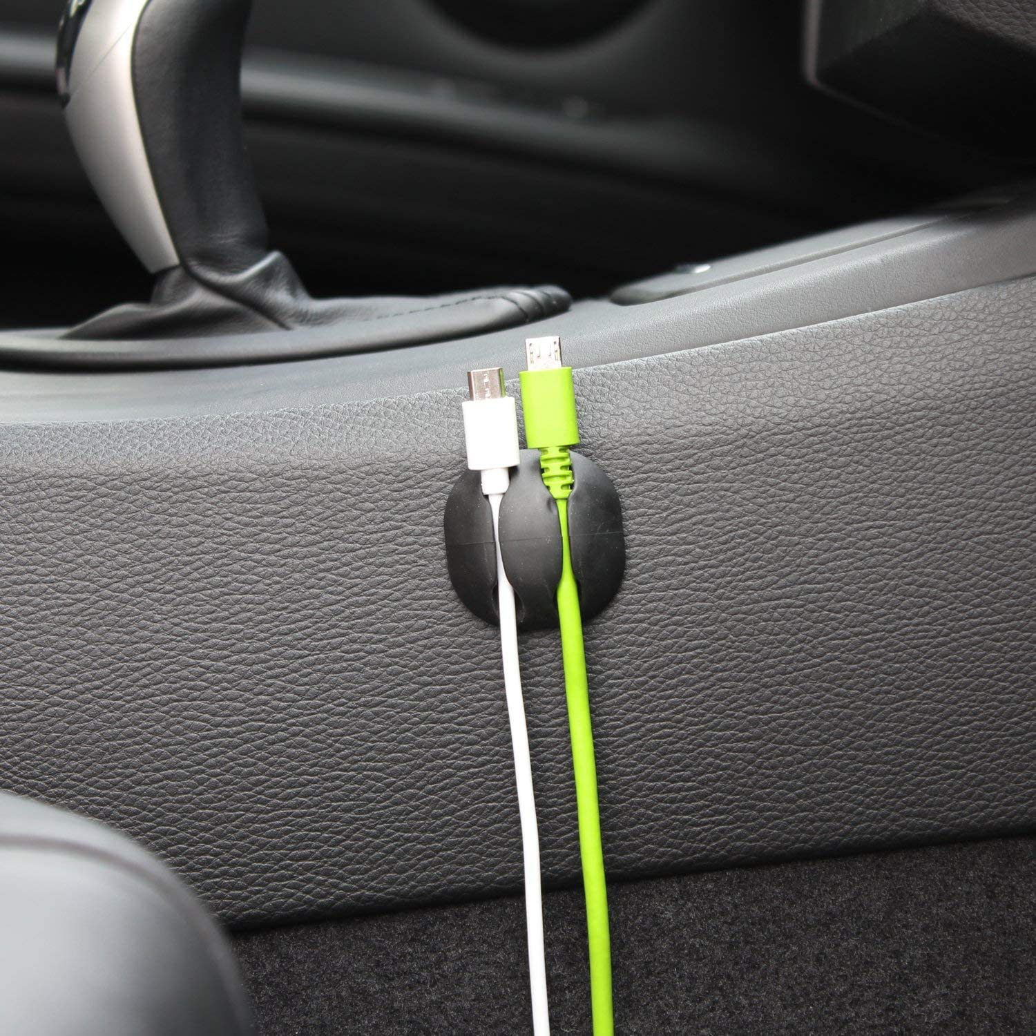 Un intérieur de voiture avec une surface noire. Deux câbles de chargement sont attachés.