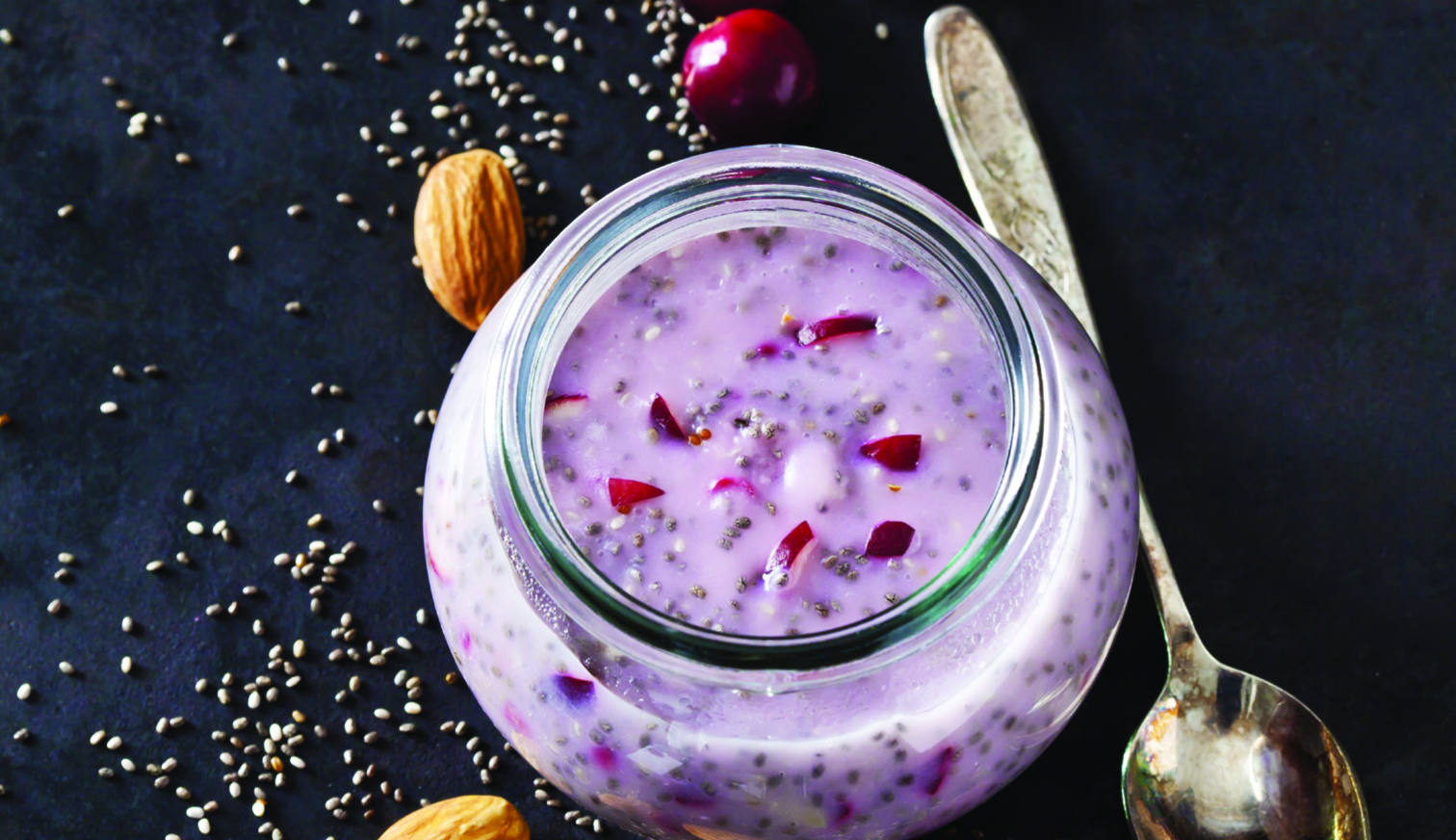 Close-up of a glass jar filled with chia seed pudding and cherries.