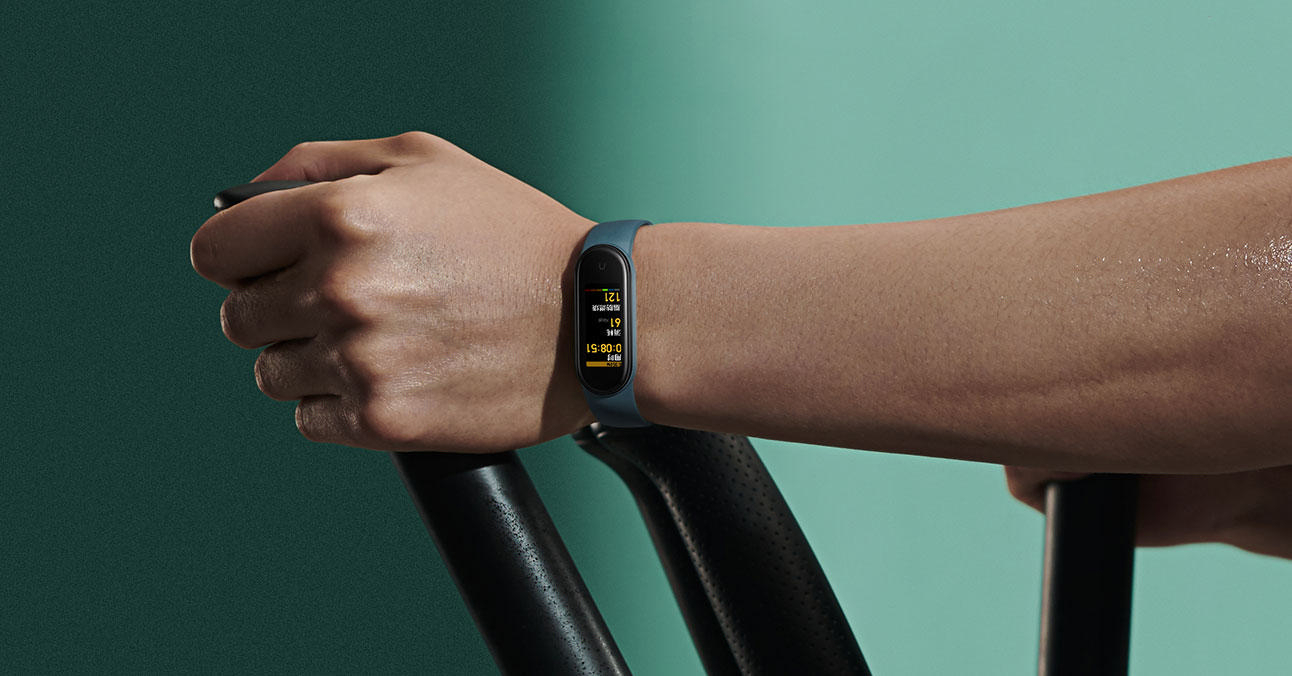 Die Hand einer Person an Trainingsgeräten mit einem Fitness-Tracker, der Metriken anzeigt.