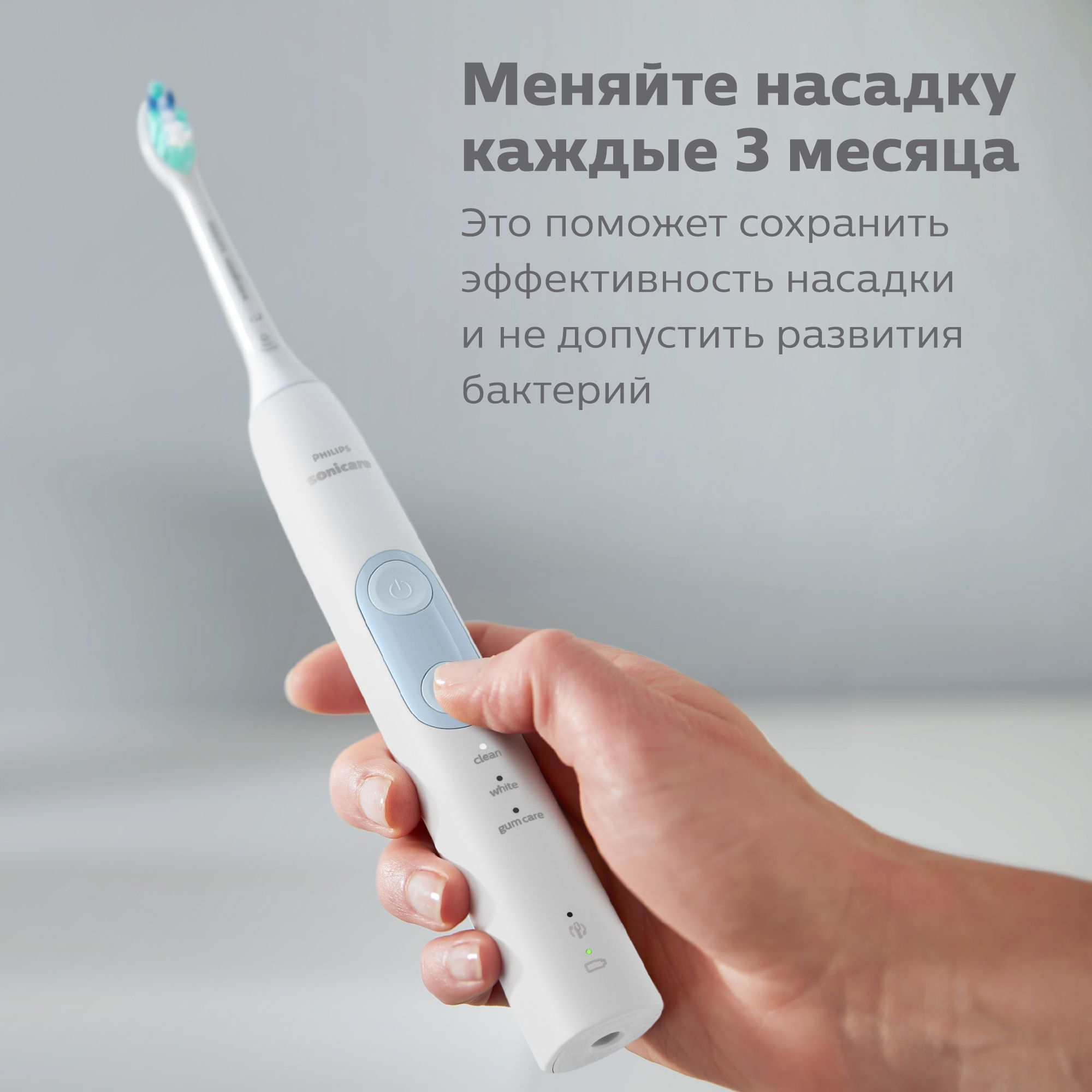 A person's hand holding a Philips Sonicare toothbrush with text in Russian.