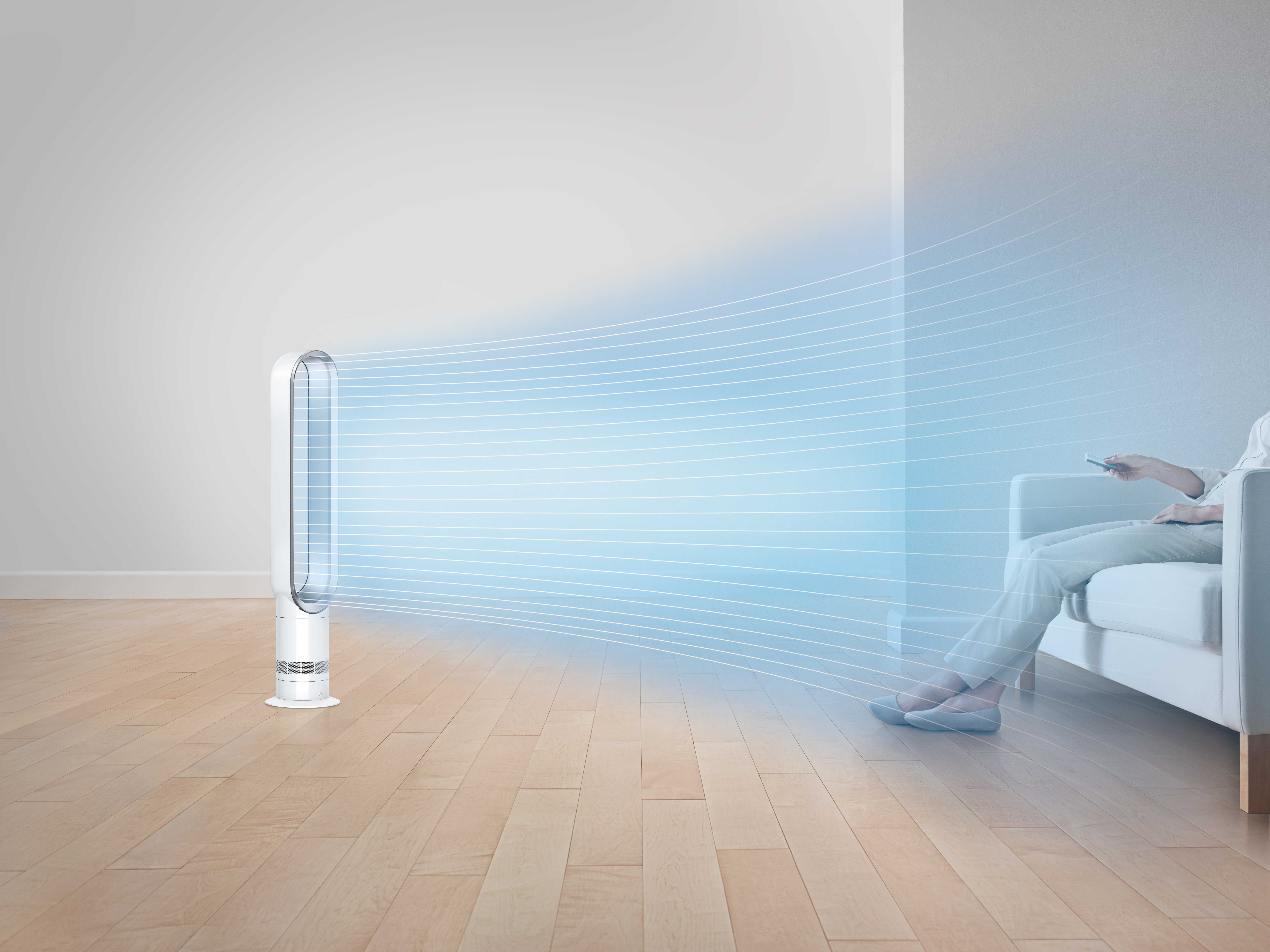 Fehér ventilátor levegőt fúj. Személy a kanapén, távirányítóval. Fa padló.